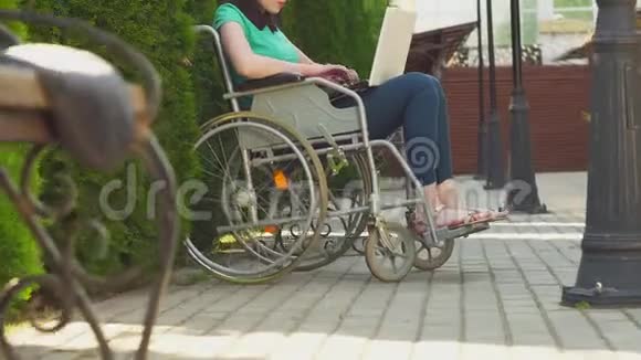 概念年轻残疾女孩坐在轮椅上手提电脑视频的预览图