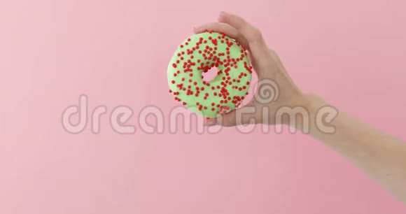 粉红色背景的女士手拿甜甜圈视频的预览图