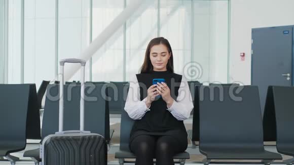 年轻漂亮的女人正在使用智能手机等待火车的到来年轻漂亮的金发女郎视频的预览图