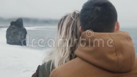 年轻漂亮的夫妇站在海边看着巨怪的脚趾岩石在冰岛有着著名的景象视频的预览图