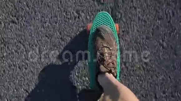 穿着运动鞋的腿在绿色滑板上视频的预览图