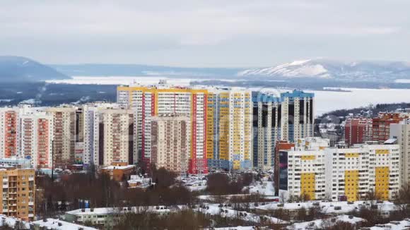冬日雪岭和河流背景中色彩鲜艳的高层建筑视频的预览图