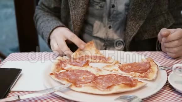 年轻英俊的女人拿着一片比萨饼咬着它饥饿的人在快餐店吃晚饭视频的预览图