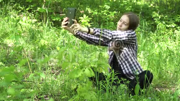 女孩在树林里用平板电脑视频的预览图