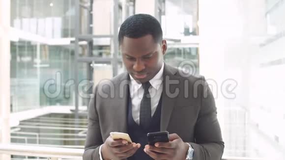 年轻的美国黑人商人用智能手机浏览站在商业中心视频的预览图