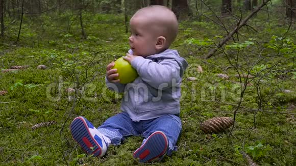 婴儿是婴儿坐在森林里吃大苹果i视频的预览图