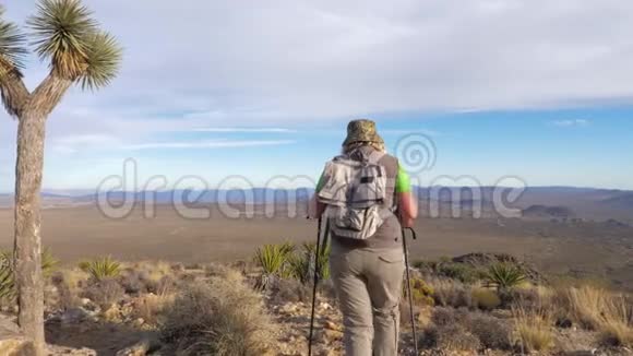 女徒步旅行者沿着莫哈韦沙漠的小径下山后景视频的预览图