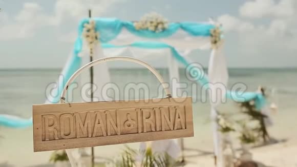 海滩上漂亮的婚礼拱门木制铭牌上面有新娘和新郎的名字结婚纪念日视频的预览图