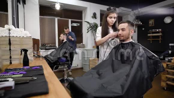 一位年轻时尚的女性发型师正在为一家美容院修剪她头部下部的头发视频的预览图