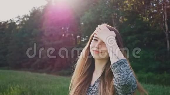 年轻而迷人的俄罗斯女孩在美丽的紫色夕阳下的绿树背景上对着镜头摆姿势视频的预览图