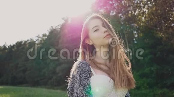年轻而迷人的俄罗斯女孩在美丽的紫色夕阳下的绿树背景上对着镜头摆姿势视频的预览图
