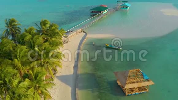 在绿松石天堂的空中观赏小热带岛屿上有船妇女和珊瑚礁视频的预览图