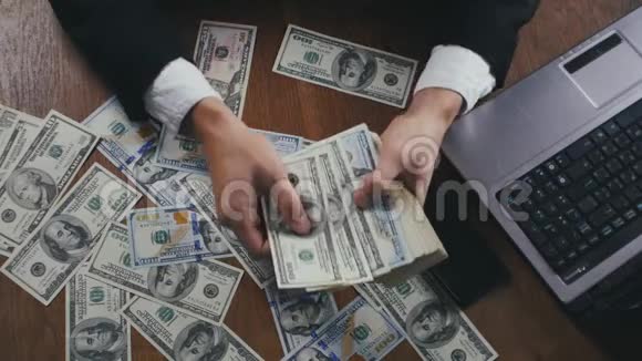 一个商人坐在办公室的桌子上数着钱紧紧地握住他的手薪酬或利润的概念视频的预览图