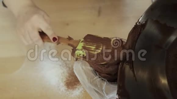 女性手将巧克力奶油或面团放入糕点袋中的特写镜头女人在厨房做饭视频的预览图