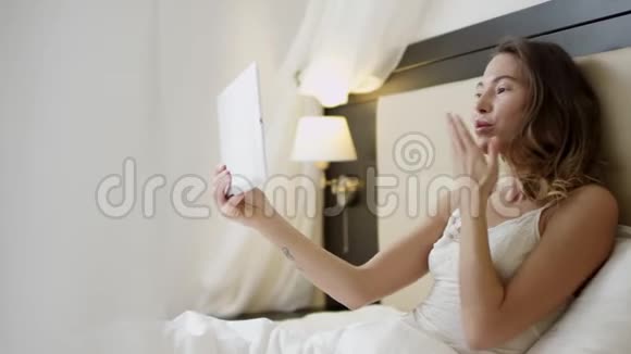 一位女士躺在床上正在通过互联网通过平板电脑进行视频对话视频的预览图