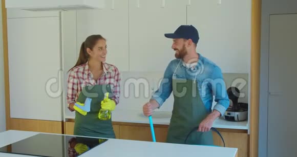 一对夫妇的肖像作为一名职业清洁工穿着制服站在一起在室内使用清洁工具视频的预览图