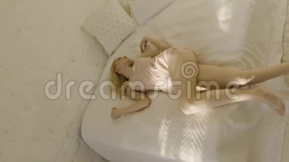 穿着粉红色睡衣的漂亮性感女人的时尚艺术行动家庭卧室内部美丽的早晨视频的预览图
