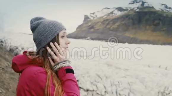 年轻的旅游妇女站在瓦特纳霍卡尔冰湖看着冰川与灰烬享受风景视频的预览图