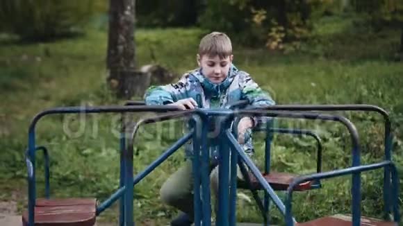 这个男孩正在院子里的一个小旋转木马上旋转游乐场视频的预览图