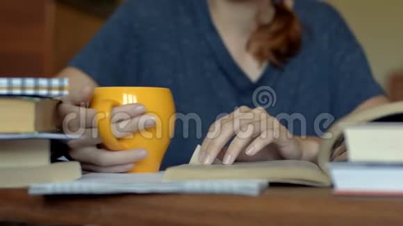 女人在桌旁看书在一个橙色的杯子里喝酒视频的预览图