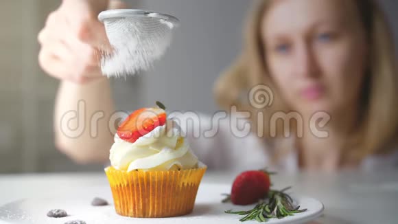 甜点厨师女性手工装饰美味的纸杯蛋糕白色奶油与切好的草莓碎片在厨房视频的预览图