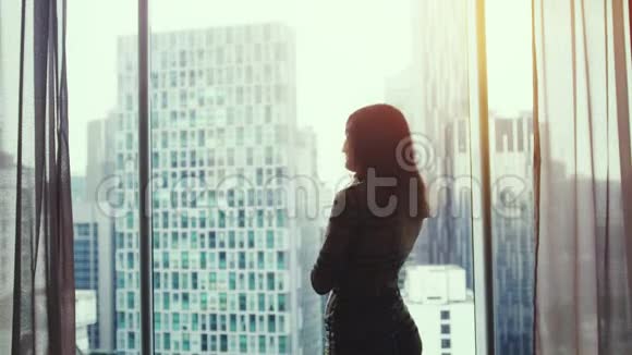 年轻的女性自由职业者或商人在豪华商务公寓的全景窗口边打电话视频的预览图