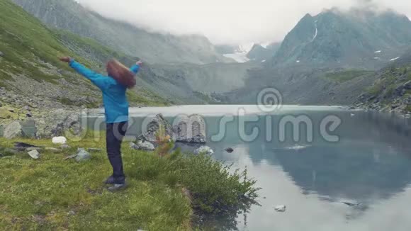 阿尔泰库切尔拉俄罗斯女孩对抗蓝色的湖泊和山脉那个女孩在旋转把手举起来4k慢速运动视频的预览图