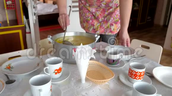 一锅汤手里拿着一个空盘子和一个瓢肉汤餐具和厨房用具上的钢制平底锅视频的预览图