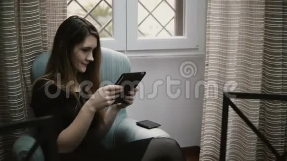 年轻漂亮的女商人坐在公寓里用平板电脑工作女性上网视频的预览图