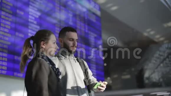 几个年轻人在机场的信息屏幕旁边拍照视频的预览图