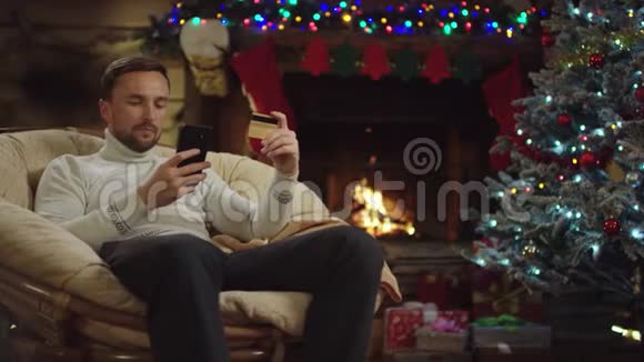 成年男子在圣诞夜使用智能手机和信用卡在线购物视频的预览图