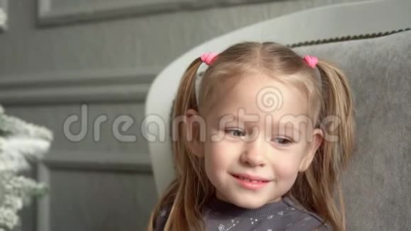 那个微笑着的金发小女孩在一棵杉树的沙发上玩耍坐在沙发上的金发小女孩微笑着视频的预览图