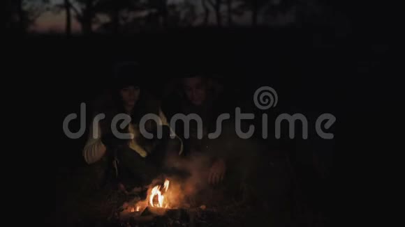 可爱的一对夫妇在森林的篝火旁休息并产生火花4K视频的预览图
