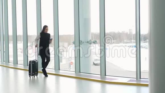 通勤车上的女商人在火车站或飞机上拿着手提行李走路时在智能手机上讲话视频的预览图