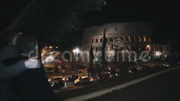 一对年轻漂亮的夫妇晚上在意大利罗马的斗兽场附近散步用手指看着视频的预览图