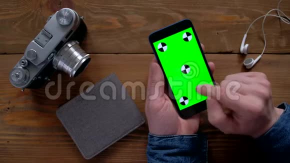 摄影师使用智能手机绿色屏幕在木桌上视频的预览图