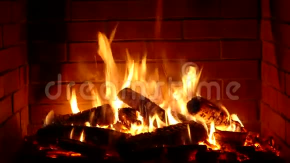 在舒适的砖砌壁炉氛围中用橘红色火焰缓慢燃烧的木头的可爱的满意特写镜头视频的预览图