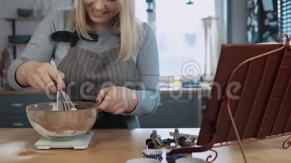 年轻漂亮的女人站在厨房里用碗里的配料和灵气搅拌做甜点视频的预览图