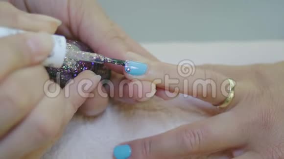 在蓝色女性指甲上涂上闪光粉视频的预览图
