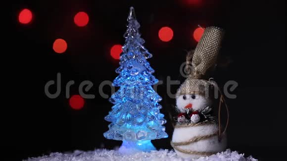 白雪皑皑的白雪中一棵圣诞树旁的雪人和五颜六色明亮的火视频的预览图