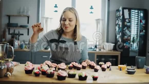 年轻的女人站在厨房里品尝巧克力蛋糕上面有奶油糖果师准备松饼视频的预览图