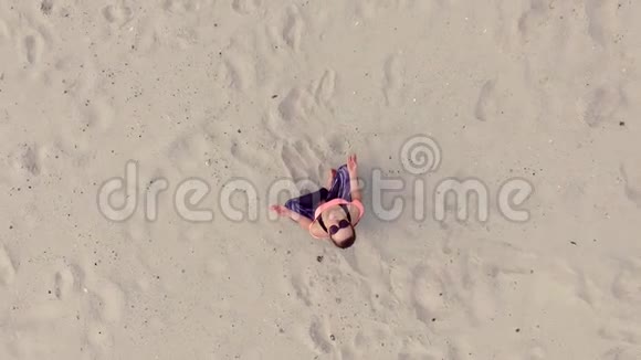 时尚的年轻美女戴着太阳镜坐在沙滩上摆出莲花的姿势冥想在一个视频的预览图