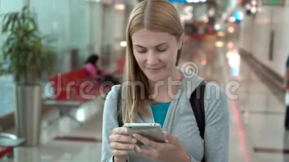 女人在机场候机楼散步使用智能手机浏览与朋友聊天阅读新闻视频的预览图
