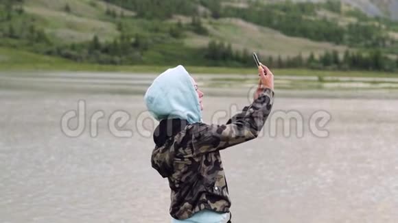 年轻的女人拿着手机坐在山里旅程视频的预览图