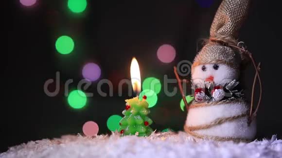 白雪皑皑的白雪中一棵圣诞树旁的雪人和五颜六色明亮的火视频的预览图