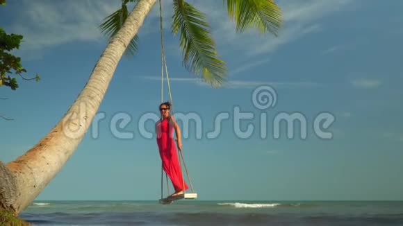 这位妇女在岛上的岸边挥杆要花钱热带海洋岸边穿着红色连衣裙的女人这就是视频的预览图