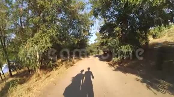 阳光明媚的日子里男人和女人走在土路上的影子视频的预览图
