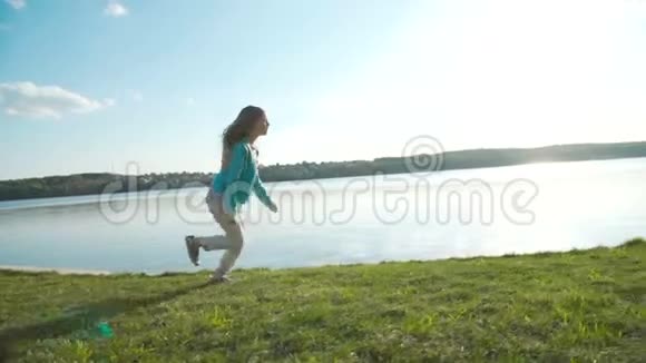 一个金发碧眼的小女孩在池塘的明亮天空下的码头上奔跑视频的预览图