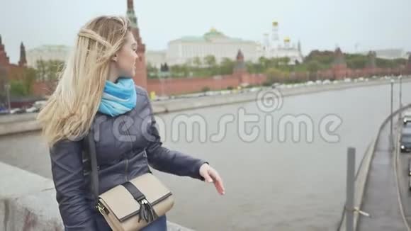 桥上的一个金发女孩在克里姆林宫的背景下向驾车者送上一个空中亲吻莫斯科俄罗斯视频的预览图