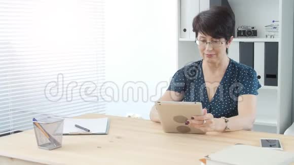 办公室的中年妇女正在制作一块平板电脑视频的预览图